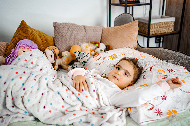 小女孩躺在病床上，裹着温暖的毯子