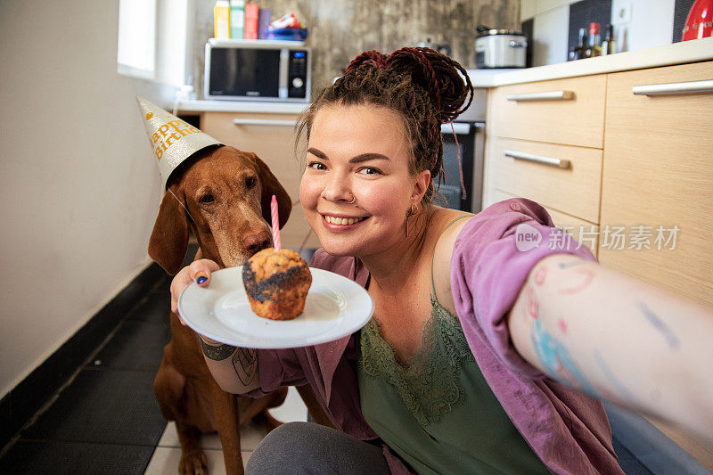 年轻女子和她的狗狗一起庆祝生日，并在自拍