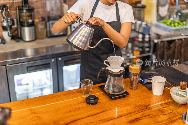 一位微笑的印尼年轻女子在咖啡馆用传统的方式准备咖啡