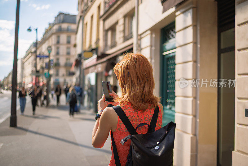 女人用智能手机在巴黎的街道上找到她的路，旅行的乐趣