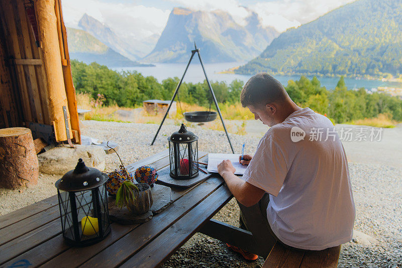 挪威峡湾风景秀丽的山间小屋内，一名旅行者正在写笔记