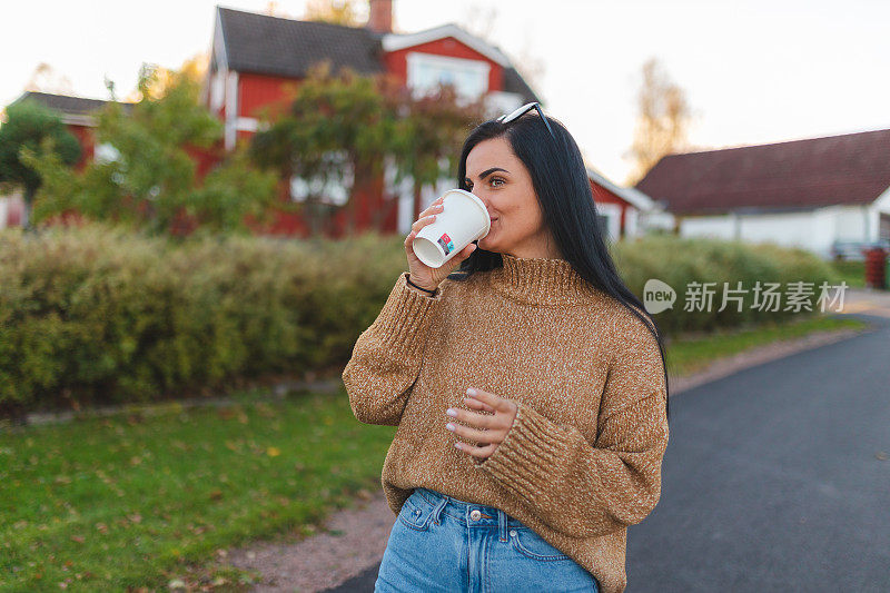 一个美丽的年轻黑发女人在郊区拿着咖啡杯的画像