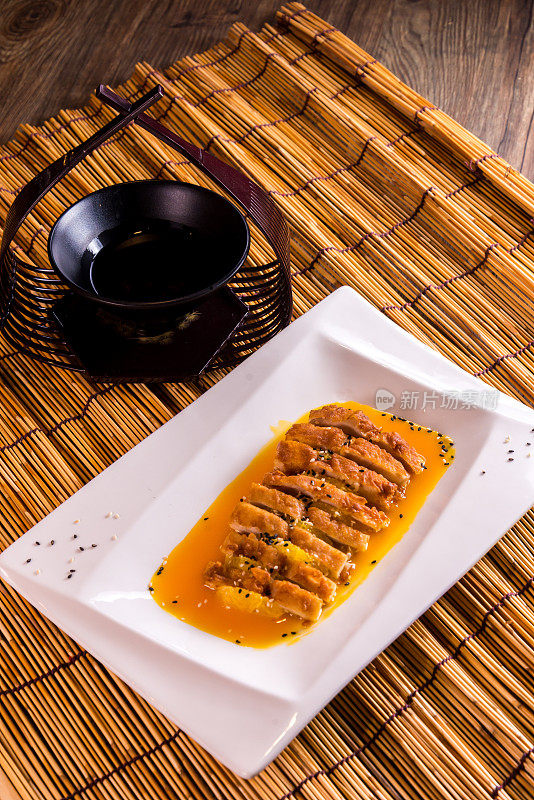 用黄酸柠檬汁煎炸鸡胸肉排，装在盘子里，放在竹木桌子上亚洲咖啡馆菜系中国餐馆宴会清真食品菜单