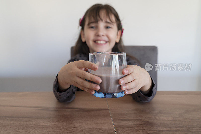 小女孩正在喝一杯巧克力牛奶