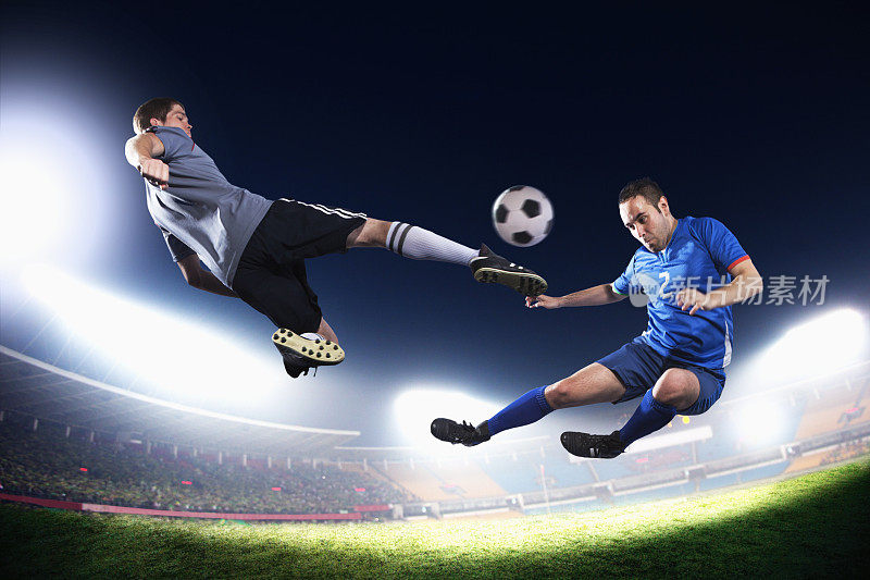 两个足球运动员在半空中踢球