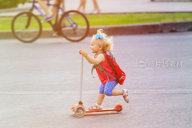 可爱的小女孩骑着滑板车在城里