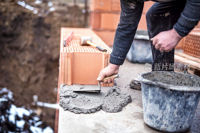 建筑工人用泥铲和水泥安装砌砖