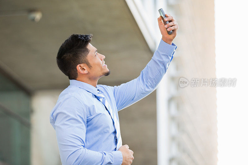 亚洲商人试图在外面用智能手机获取信号