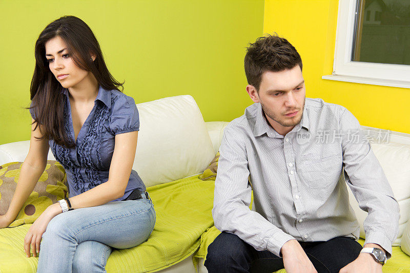 一对不开心的年轻夫妇坐在客厅里。