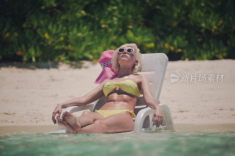 在马尔代夫的浅水里晒日光浴，坐在安乐椅上休息
