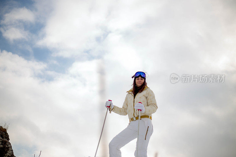 近景美丽的年轻女子在冬天的衣服站在一边，手拿木棍的背景雪山