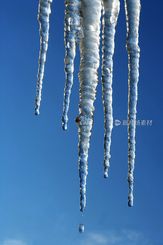 蓝色天空背景上融化的冰柱