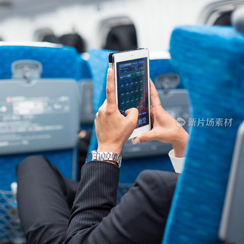 商人在飞机上使用平板手机。