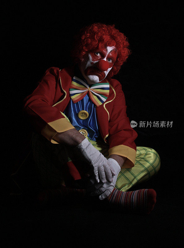 悲伤的小丑坐在地板上