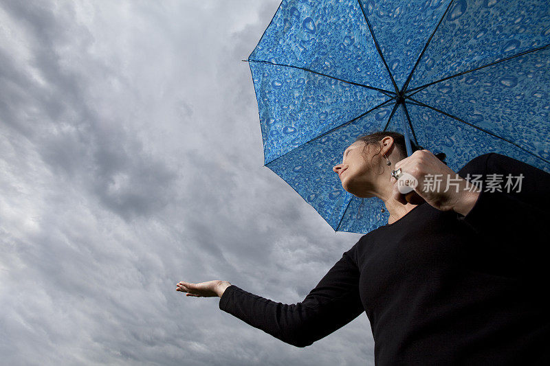 女人撑着伞伸手检查是否下雨