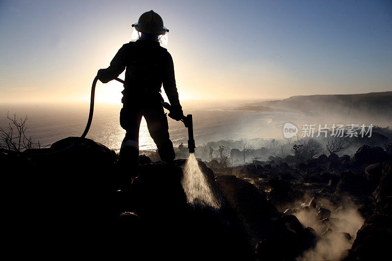 一个消防员正在扑灭丛林大火的剪影