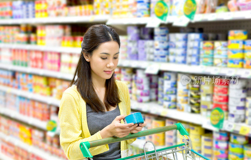 亚洲妇女在超市买罐头