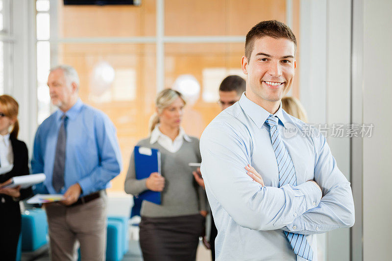 自信的年轻商人在办公室摆姿势拍照。