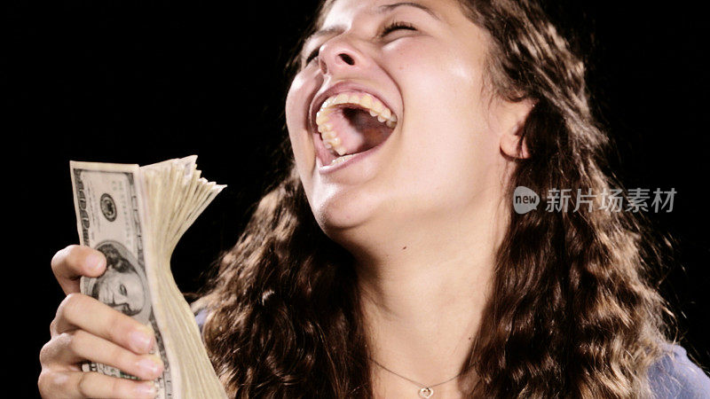 抱着一捆钞票的年轻女子喜出望外，兴奋地笑了