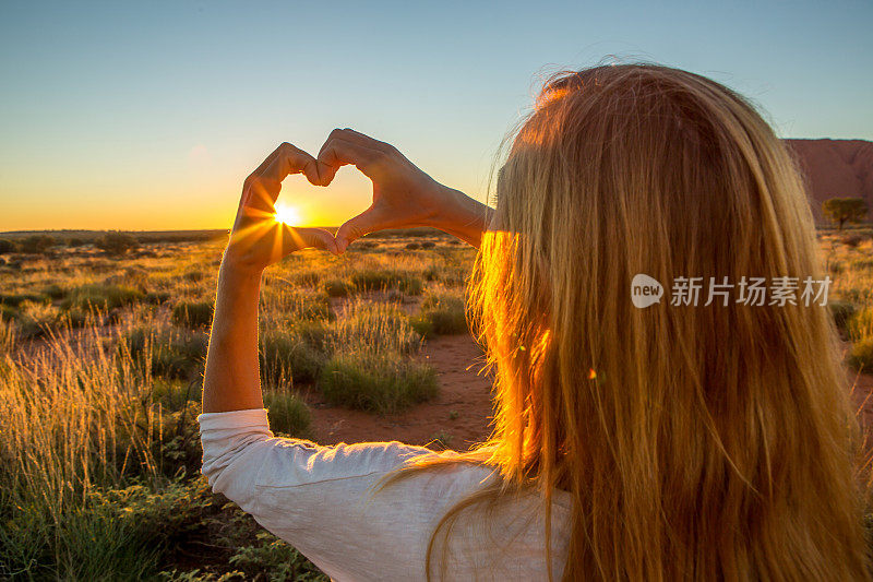 女人把夕阳画成心形的指框