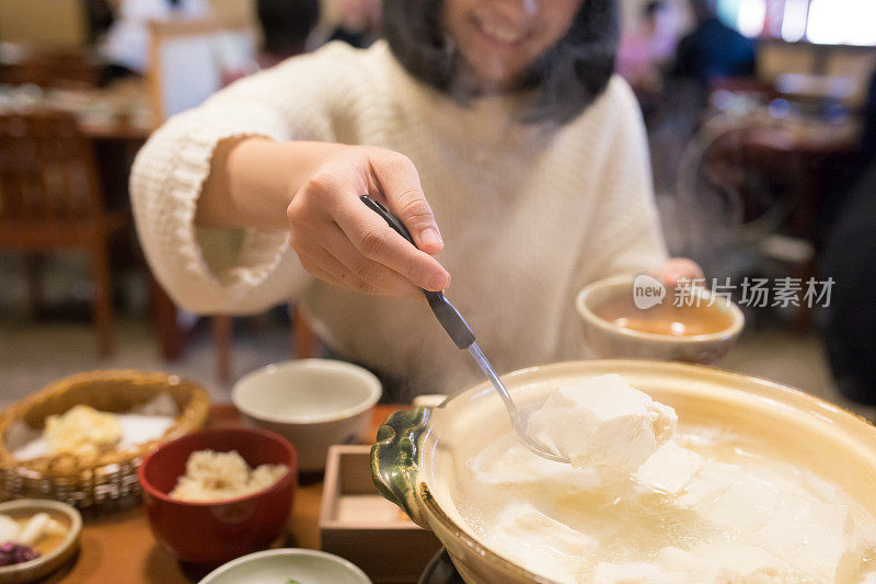 年轻女子从火锅里捡豆腐