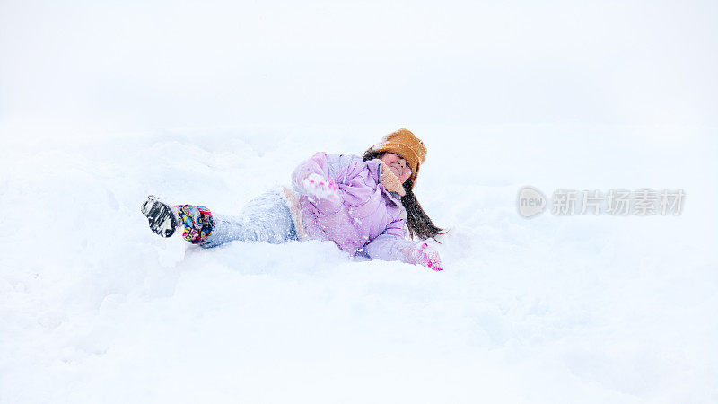 小女孩高兴地在雪地里打滚