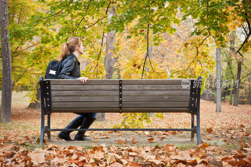 秋天里坐在公园长椅上的女人