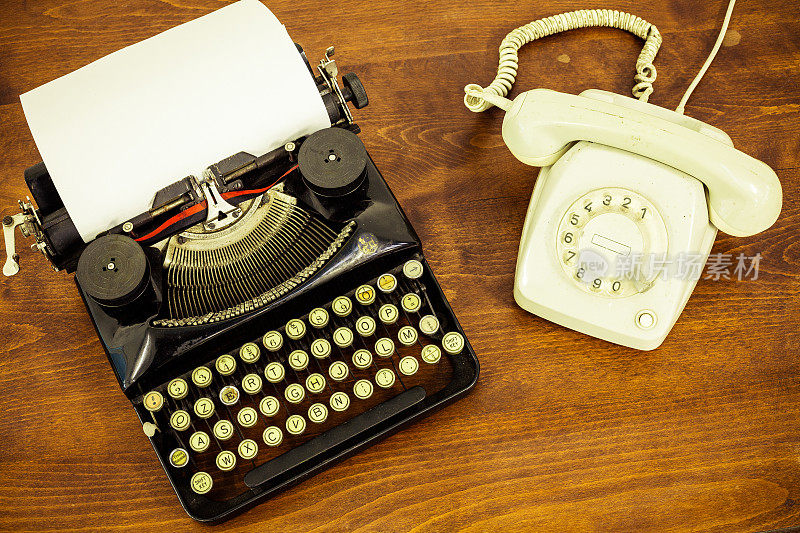 老式打字机和老式电话在木桌上
