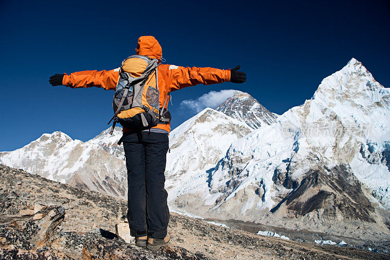 徒步者举起她的手臂胜利，珠穆朗玛峰为背景