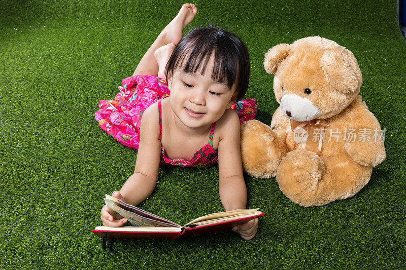 亚洲华人小女孩和泰迪熊一起看书