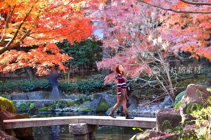 年轻的日本女人走在日本花园的石桥上，东京