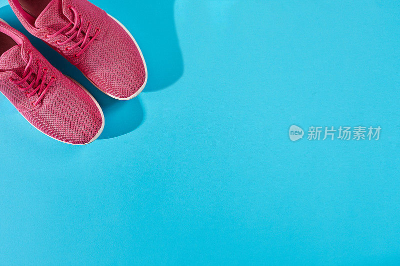 新的粉红色运动鞋在蓝色背景与复制空间。体育的概念