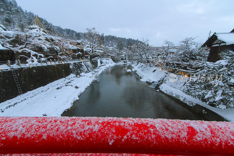 从高山县的红桥上看，宫川河上覆盖着积雪和古老的建筑，中桥附近的日式房子就在旁边