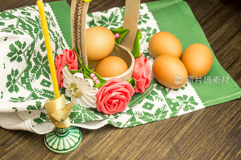 复活节俄罗斯静物画。鸡蛋放在花篮里，糖果，面包卷，在传统的餐巾上的木制背景上准备休息。