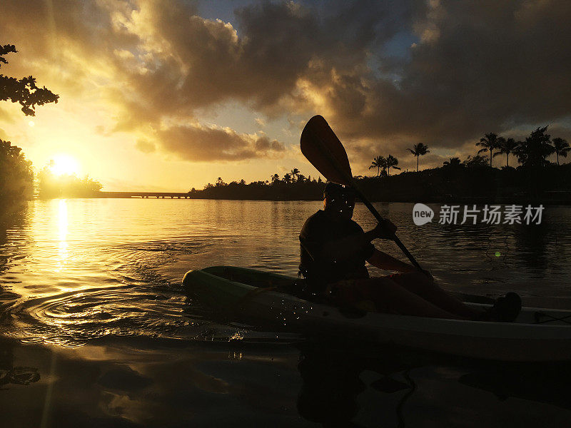 清晨的阳光沐浴在天空中，人们在外陆河上划着皮艇