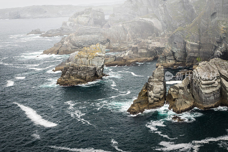 岩石嶙峋的岬角，海浪拍打着海岸线，还有薄雾