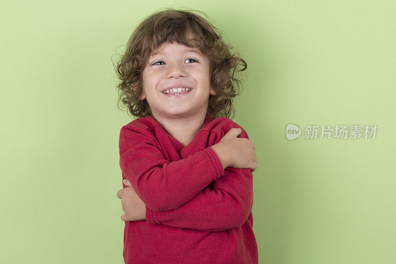 婴儿在绿色背景，快乐的孩子三岁，微笑的孩子男孩坐在红色的衣服