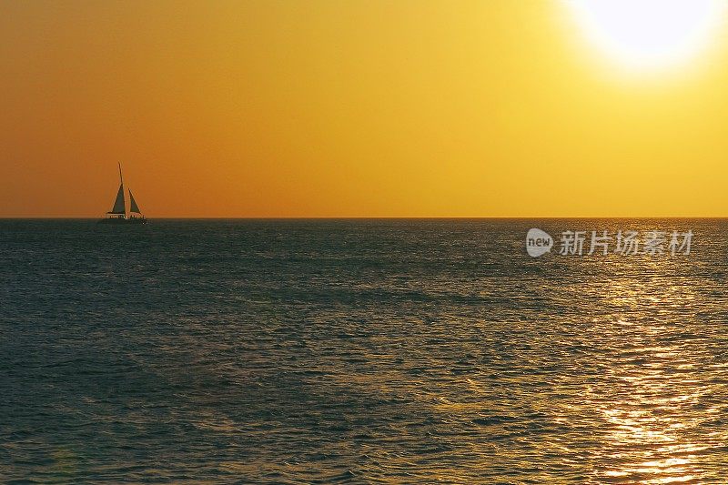 热带天堂:帆船游艇航行在戏剧性的日落-阿鲁巴，加勒比海