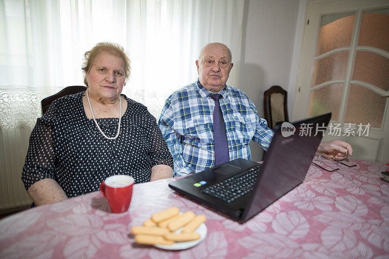 六十年在一起。老夫妇在家里用笔记本电脑喝咖啡吃饼干