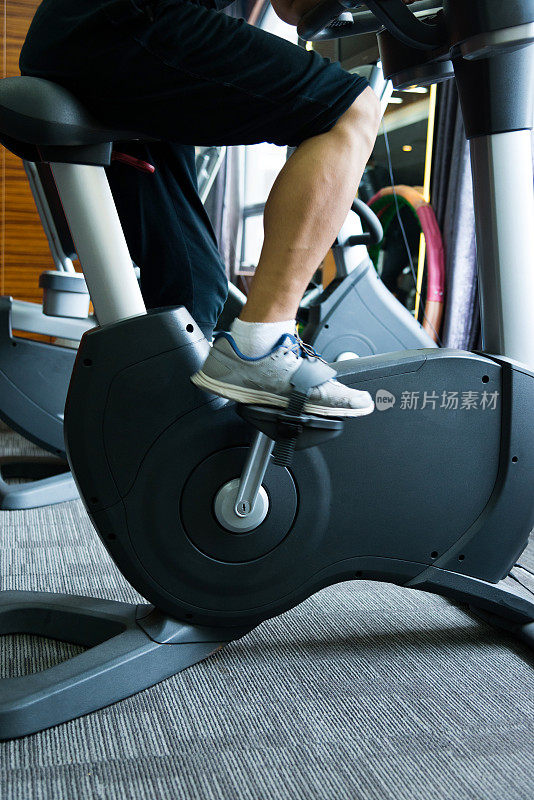 在健身房里骑着健身自行车锻炼的男人