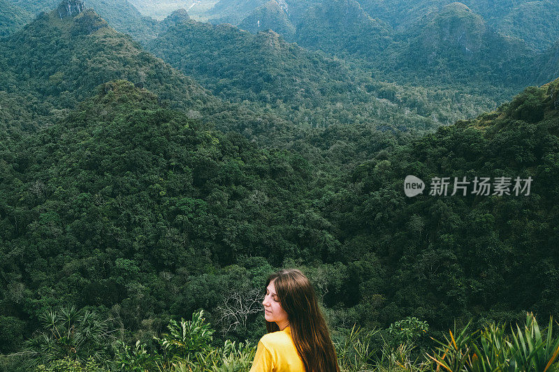 一名女子在山顶休息，欣赏越南吉巴岛的丛林景色