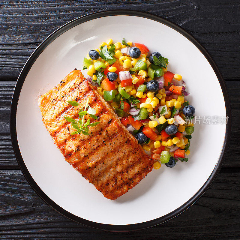 健康食物:烤三文鱼片配辣椒、玉米、蓝莓和洋葱沙拉。从上面俯视
