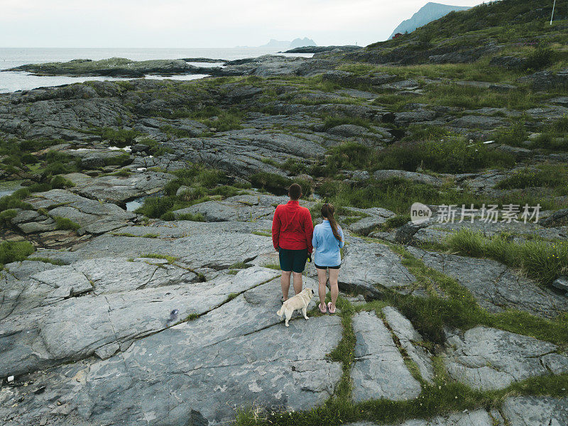 在罗浮敦群岛上，一对夫妇抱着狗看海