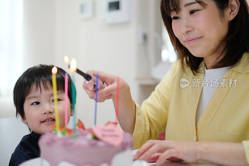 妈妈在儿子的生日蛋糕上点蜡烛