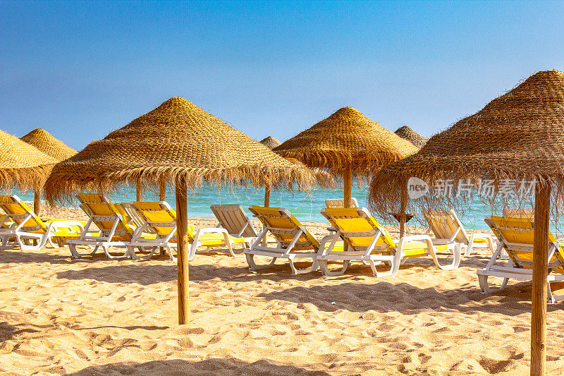近距离观看躺椅和遮阳伞在Albufeira海滩，阿尔加维，葡萄牙。