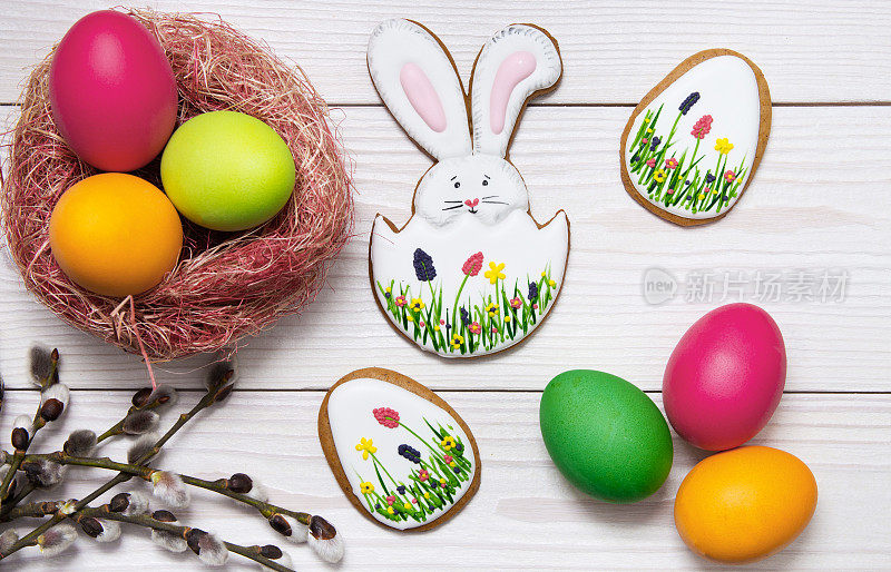 姜饼复活节以白色的木头为背景，画上彩蛋和柳枝。复活节兔子和鸡蛋，姜饼