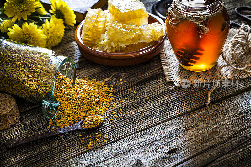 蜂蜜罐，蜂花粉和蜂窝放在质朴的木桌上