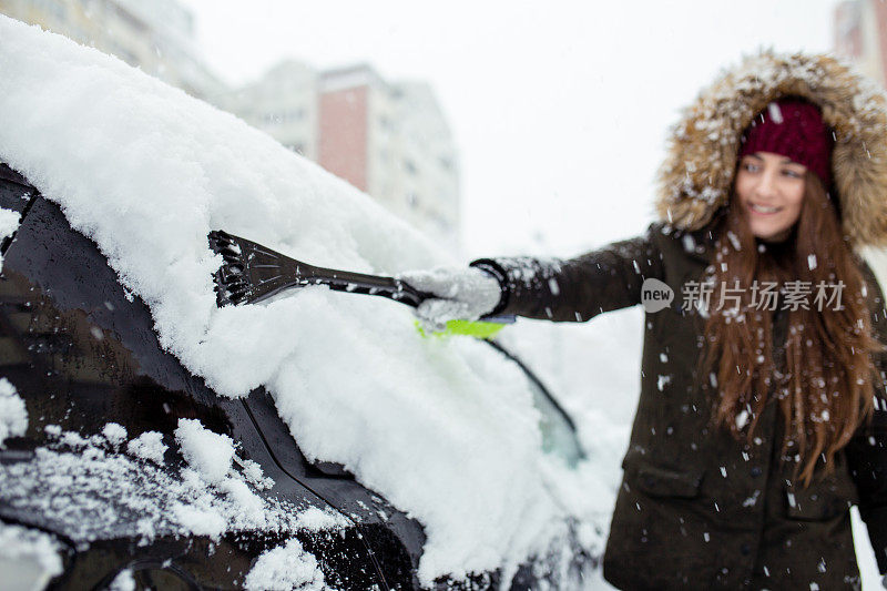 年轻女子在清理车上的积雪