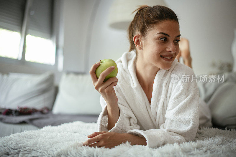 健康食品，饮食，生活方式，饮食概念。床上放着苹果的女人