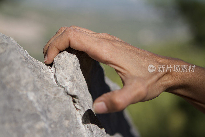 年轻女子攀岩者双手攀爬在悬崖峭壁上